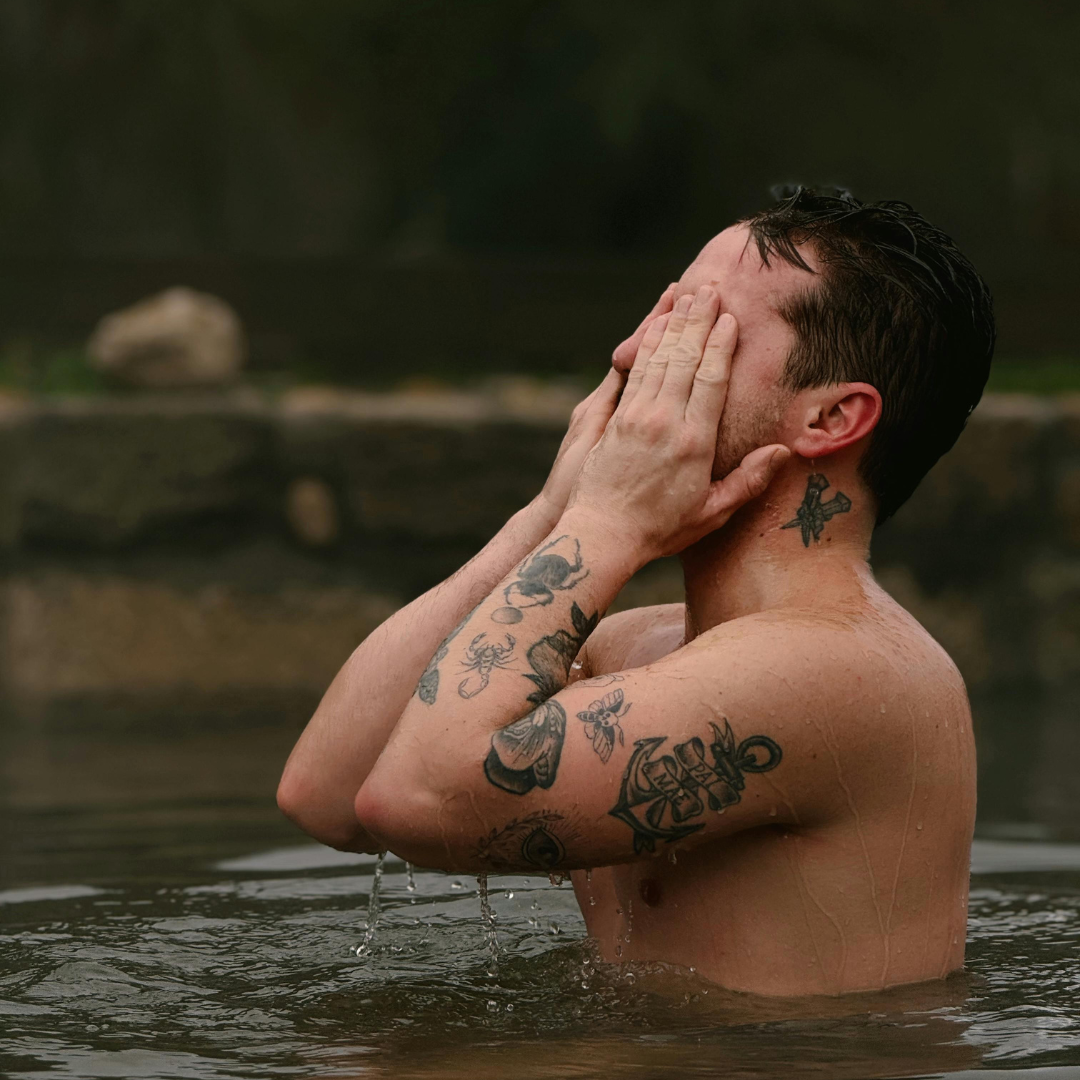Man with tattoos covering his face in a natural setting
